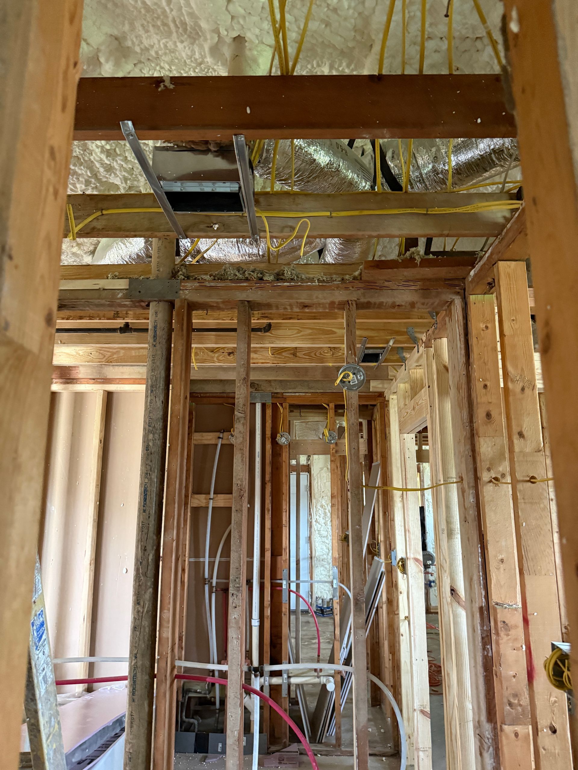 Interior of a framed house under construction with exposed wood studs, wiring, and ceiling ductwork