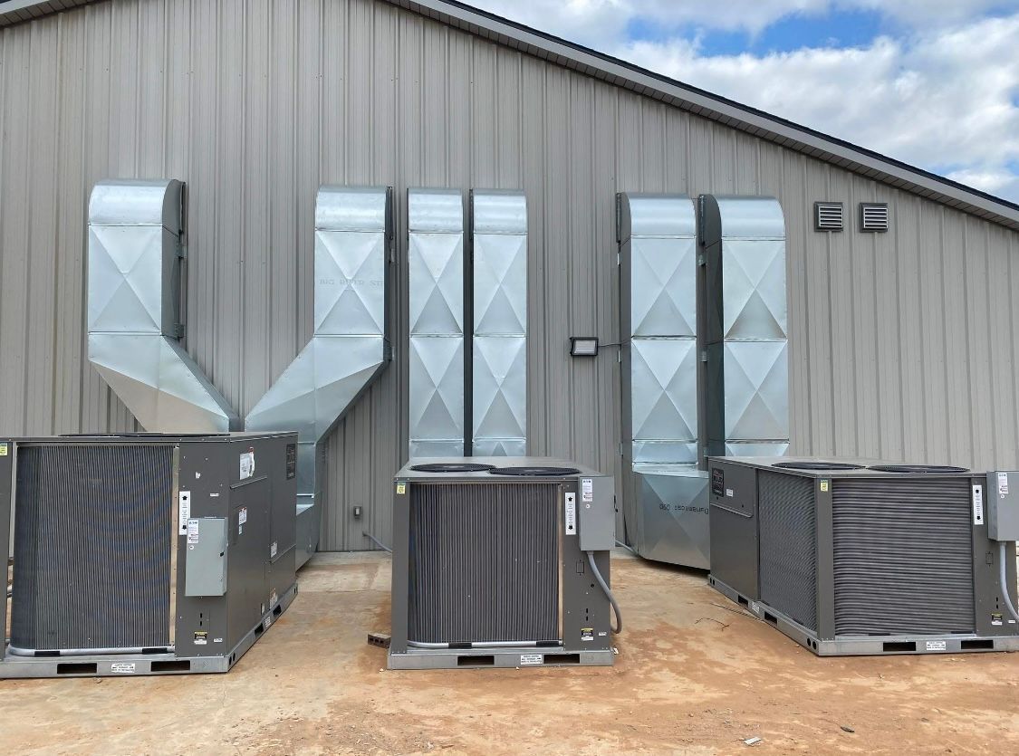 Industrial building exterior with large HVAC units and silver ventilation ducts on the wall