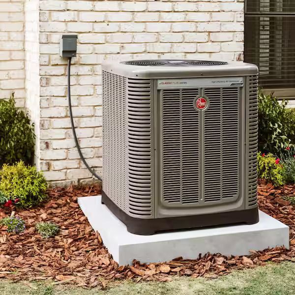 Outdoor air conditioning unit on a concrete pad beside a brick house wall.