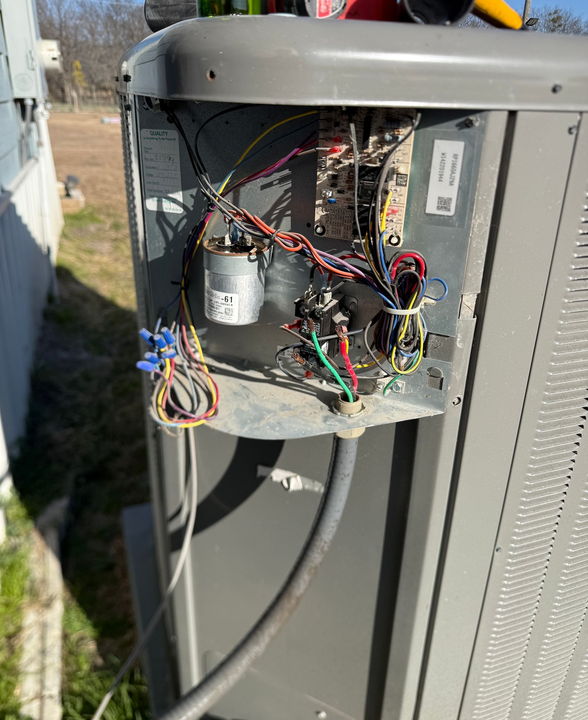 Open outdoor electrical unit with exposed wiring and components inside a gray metal cabinet.