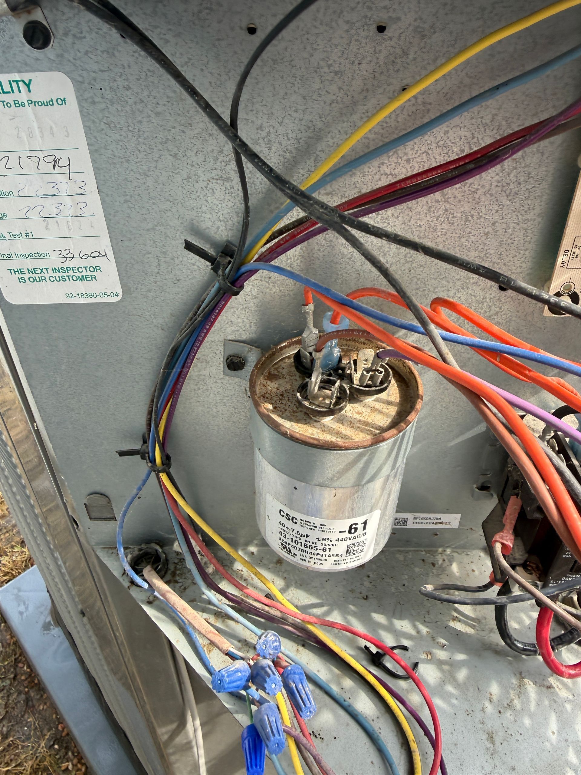 Wiring inside a metal electrical box with a cylindrical capacitor and bundled red, yellow, and blue wires