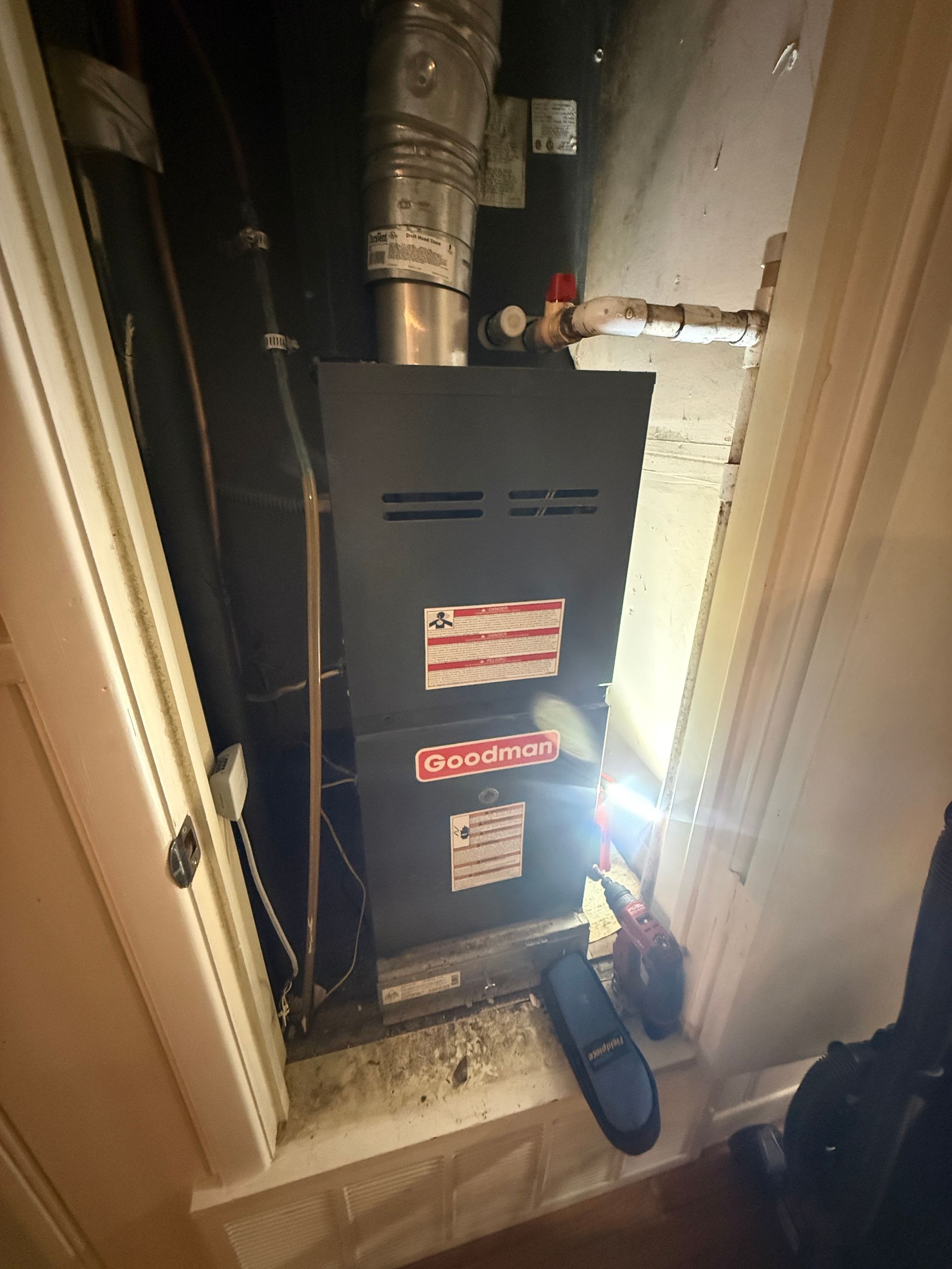 Basement furnace with exposed pipes and a flashlight shining beside it