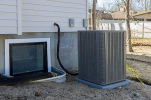 House exterior with a basement window, HVAC unit, and utility lines along the foundation