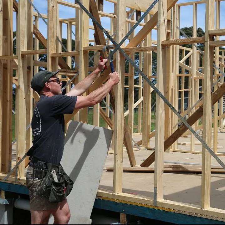 Man using tool on diagonal bracing for wooden house frame.