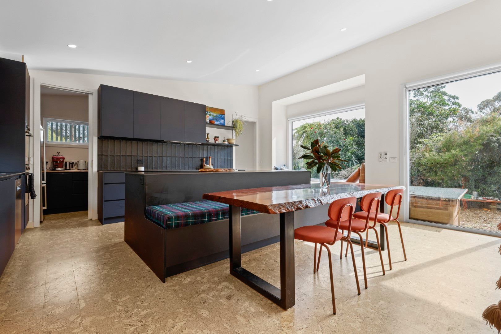 Modern kitchen with dark cabinetry, island with bench seating, and dining table.