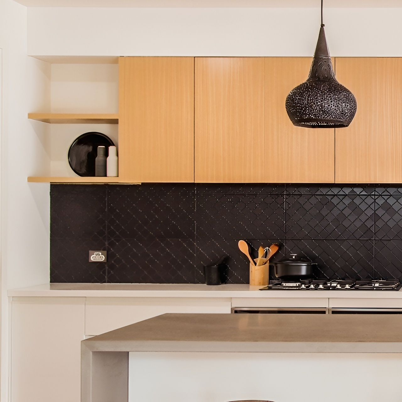 Modern kitchen with wood cabinets, black tile backsplash, and hanging black light fixture.