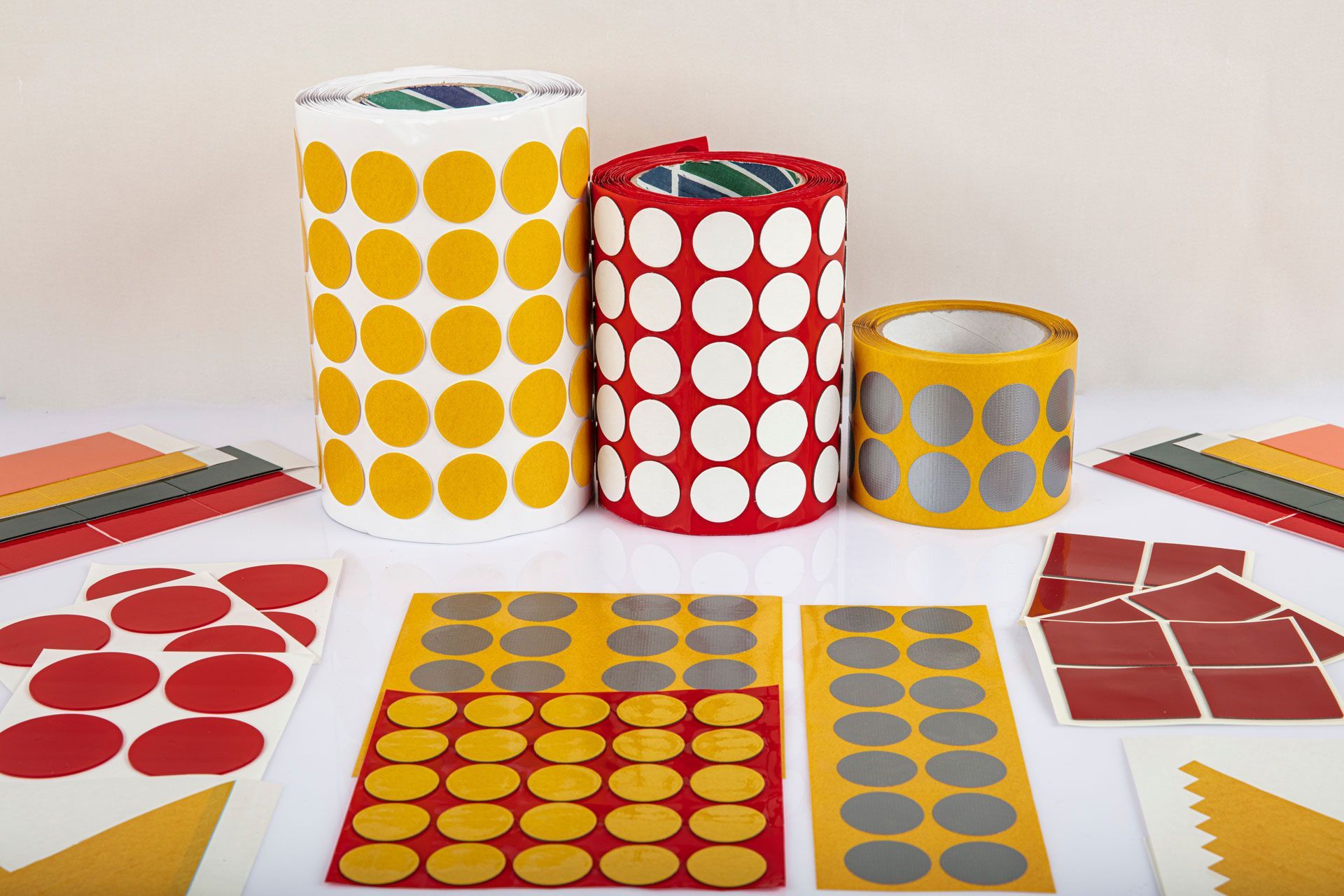Rolls and sheets of various adhesive label stickers in yellow, white, red, and silver.