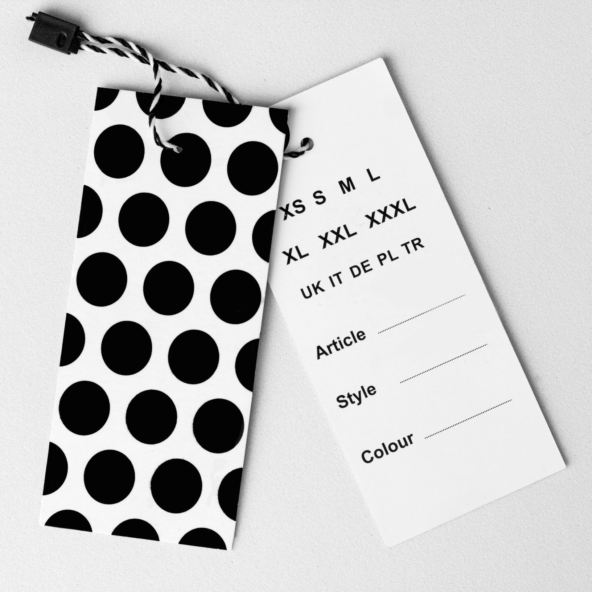A hanging clothing tag with a black and white polka dot pattern and a blank information template for sizes and details.