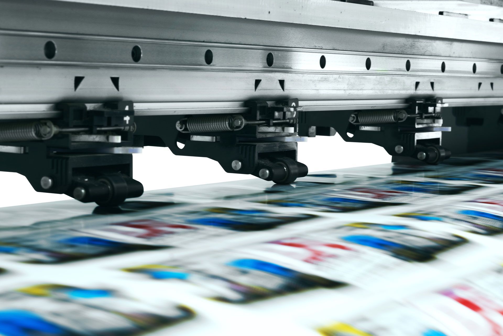 Close-up of a high-speed printing press mechanism rolling over a sheet with repeating colorful graphic patterns.