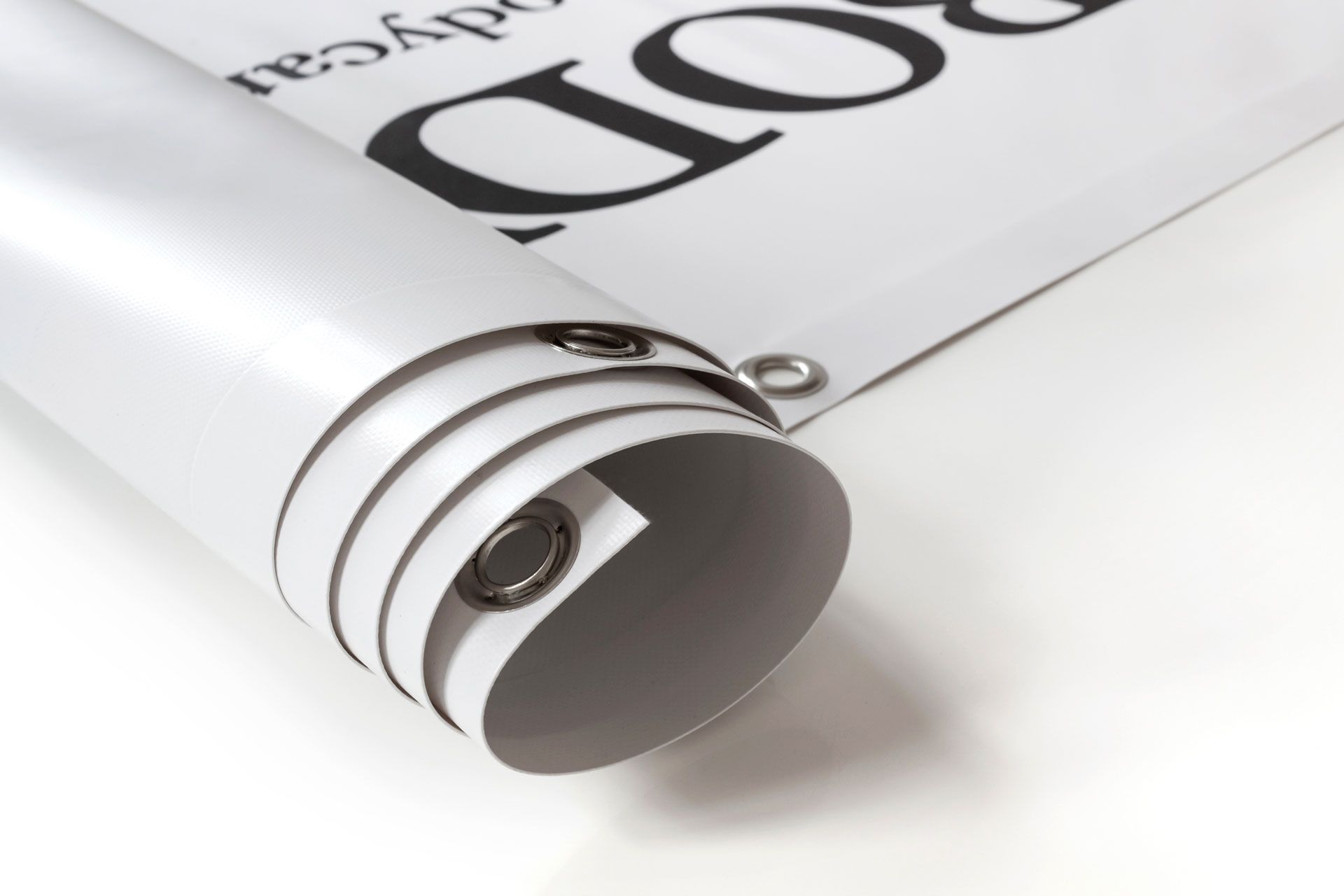 A white rolled vinyl banner with metal grommets along the edge, showing partial black text.