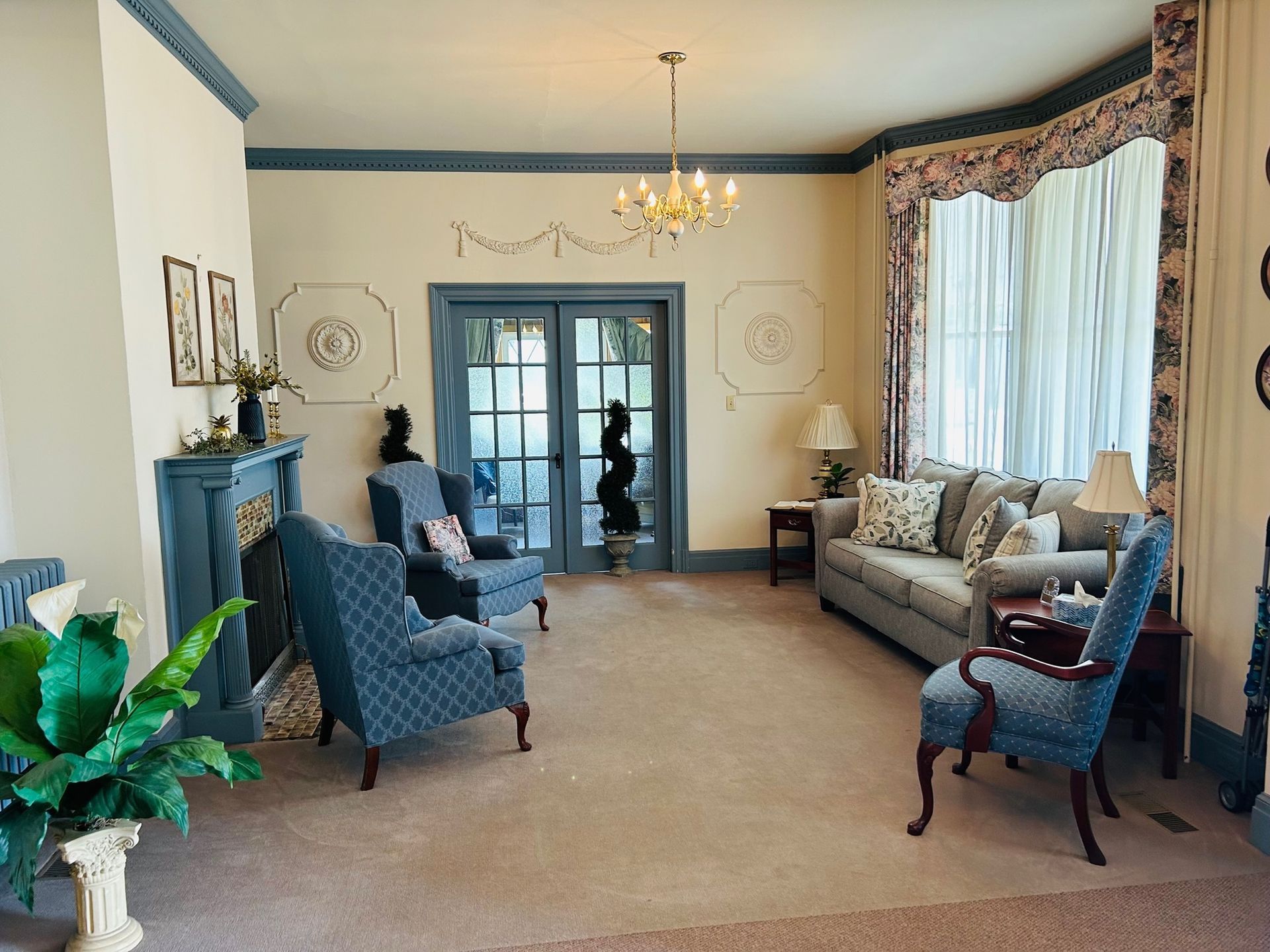 Elegant living room with blue accents, fireplace, chairs, and sofa; a doorway leads outside.