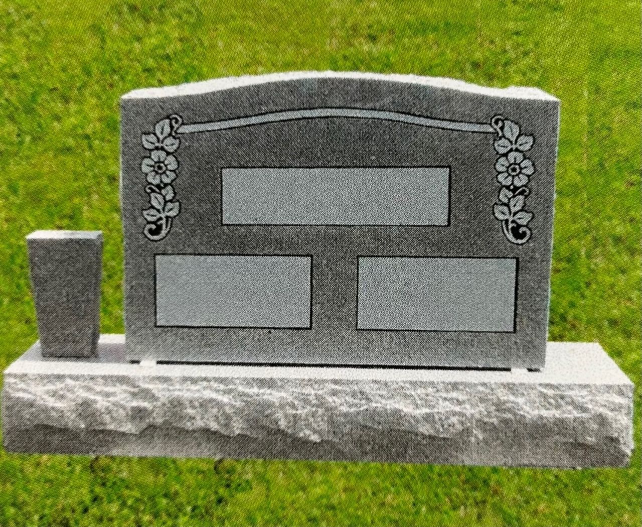 Gray granite headstone with floral designs and blank panels, set on a stone base, green grass background.