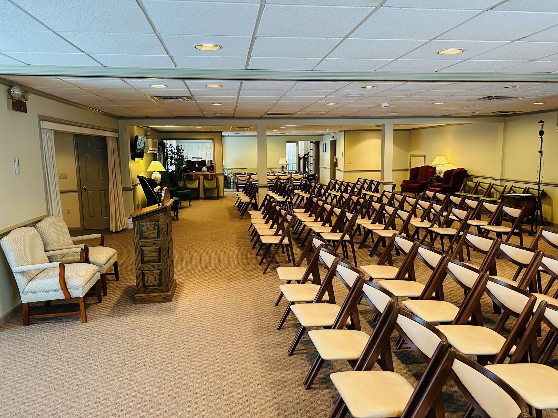 A room prepared for a ceremony, with rows of chairs, a podium, and seating in front.