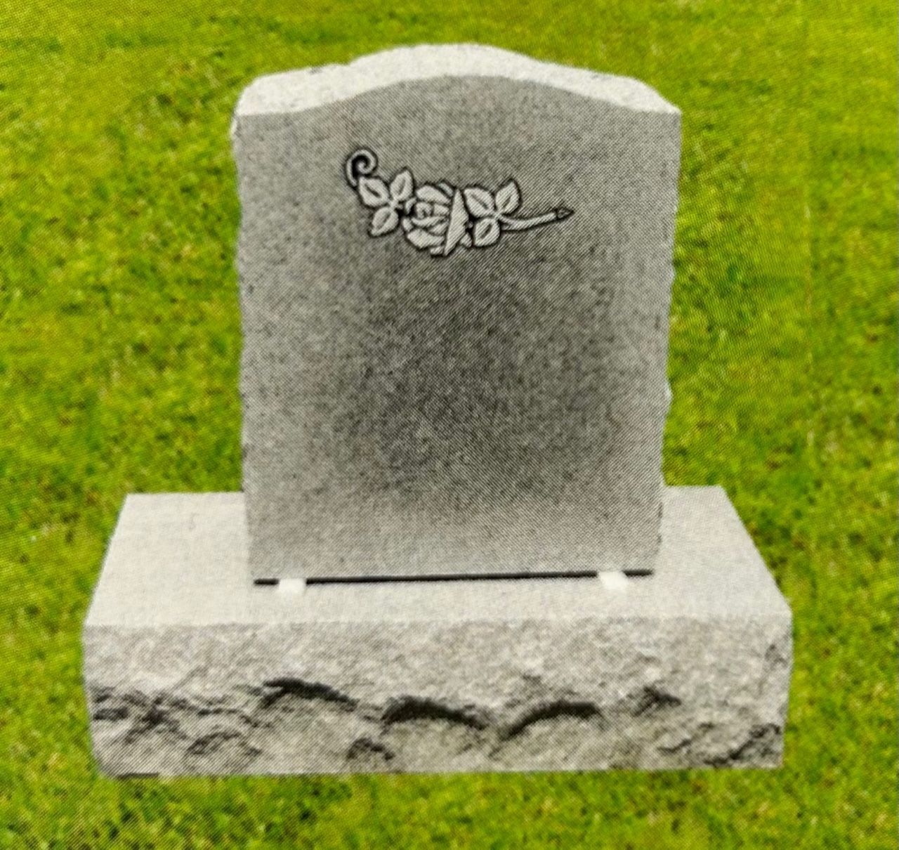 Gray granite headstone with a rose carving, on a matching base in a grassy setting.