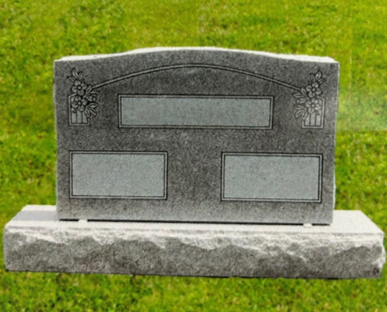 Gray granite headstone with blank inscription panels and floral details, on a grass background.