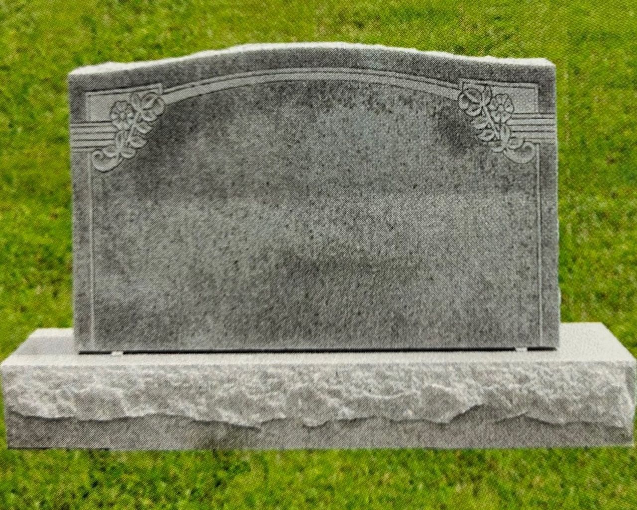 Gray granite headstone with decorative floral details against green grass.