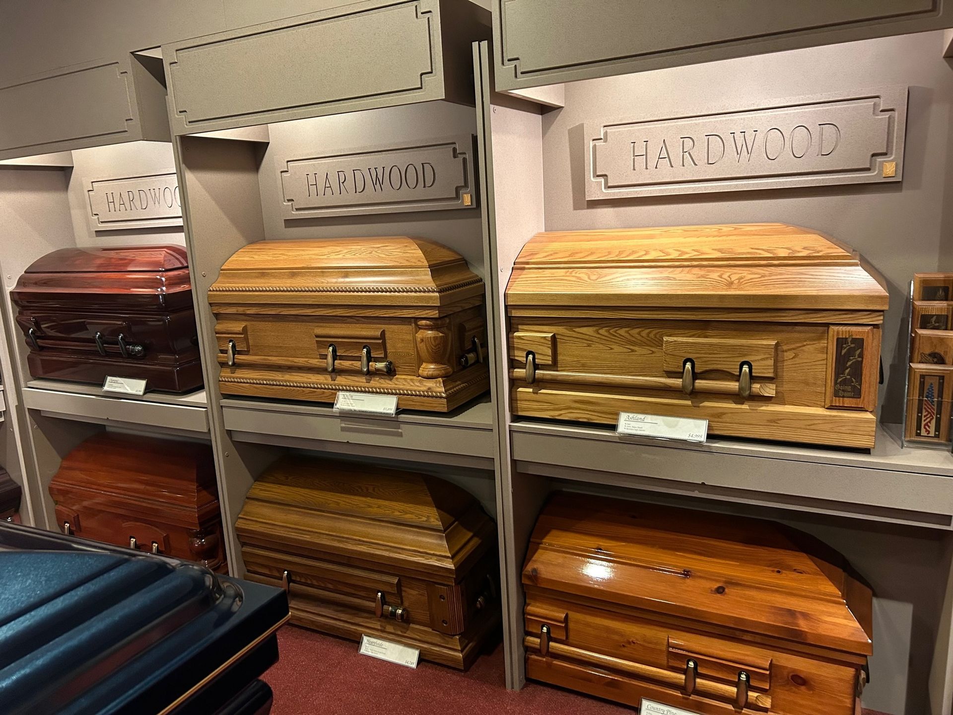 Wooden caskets on display in a store, labeled 