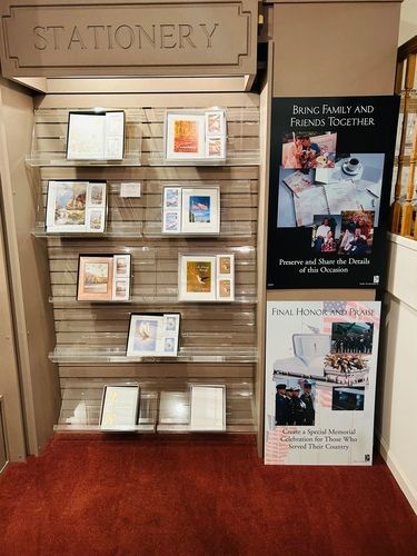 Stationery display in a shop, showcasing various cards and photo frames on shelves; a red carpet below.