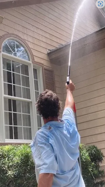 A man is cleaning a patio with a high pressure washer.