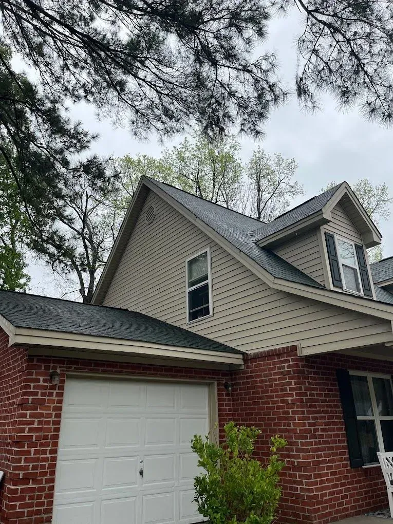 A brick house with a white garage door and a black roof.