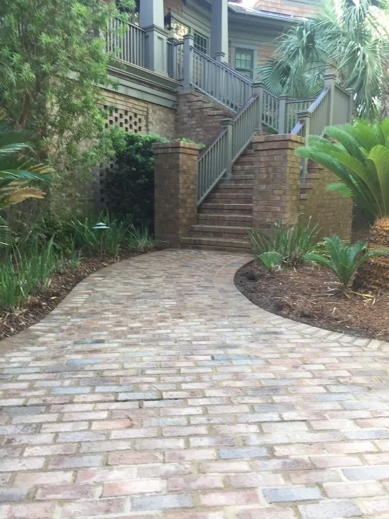 A brick walkway leading up to a house with stairs.