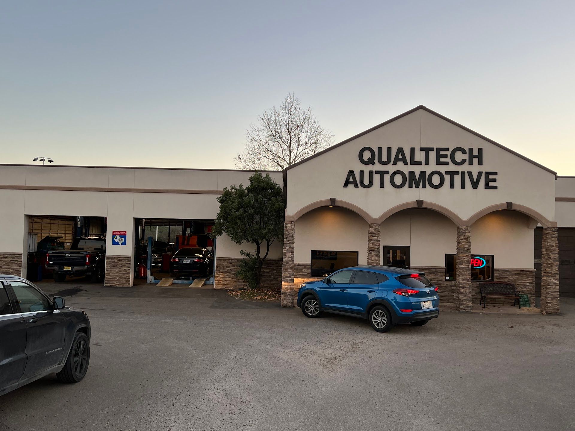 Qualtech Automotive building with cars parked outside; a blue SUV is center. | QualTech Automotive