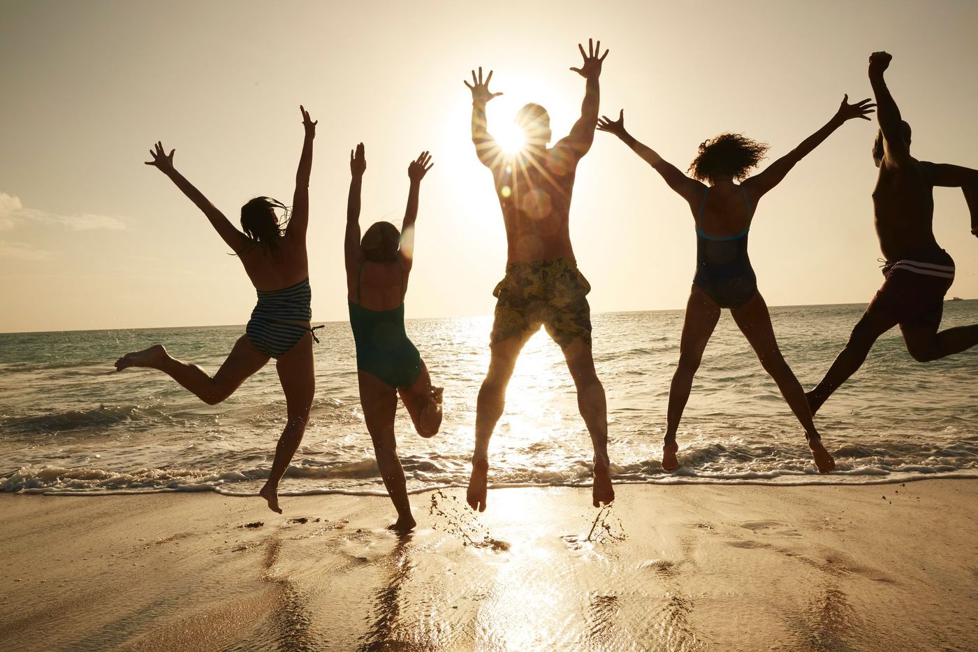 A group of people are jumping in the air on the beach