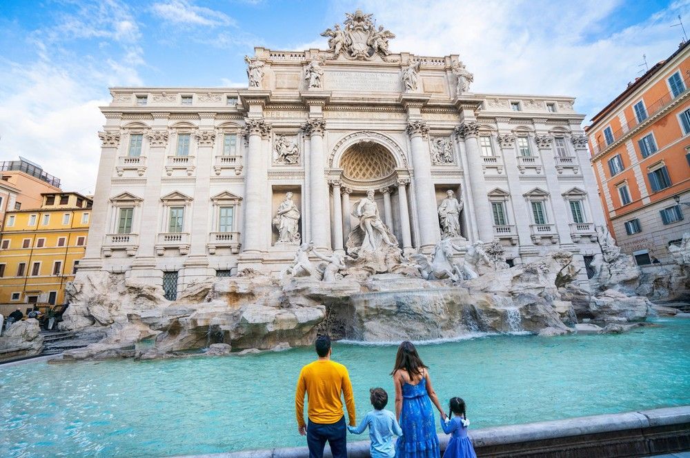 A family is standing in front of a fountain in rome.