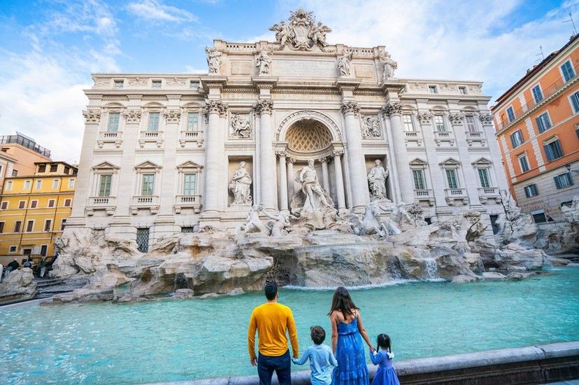 A woman wearing a hat and sunglasses is standing next to a fence.