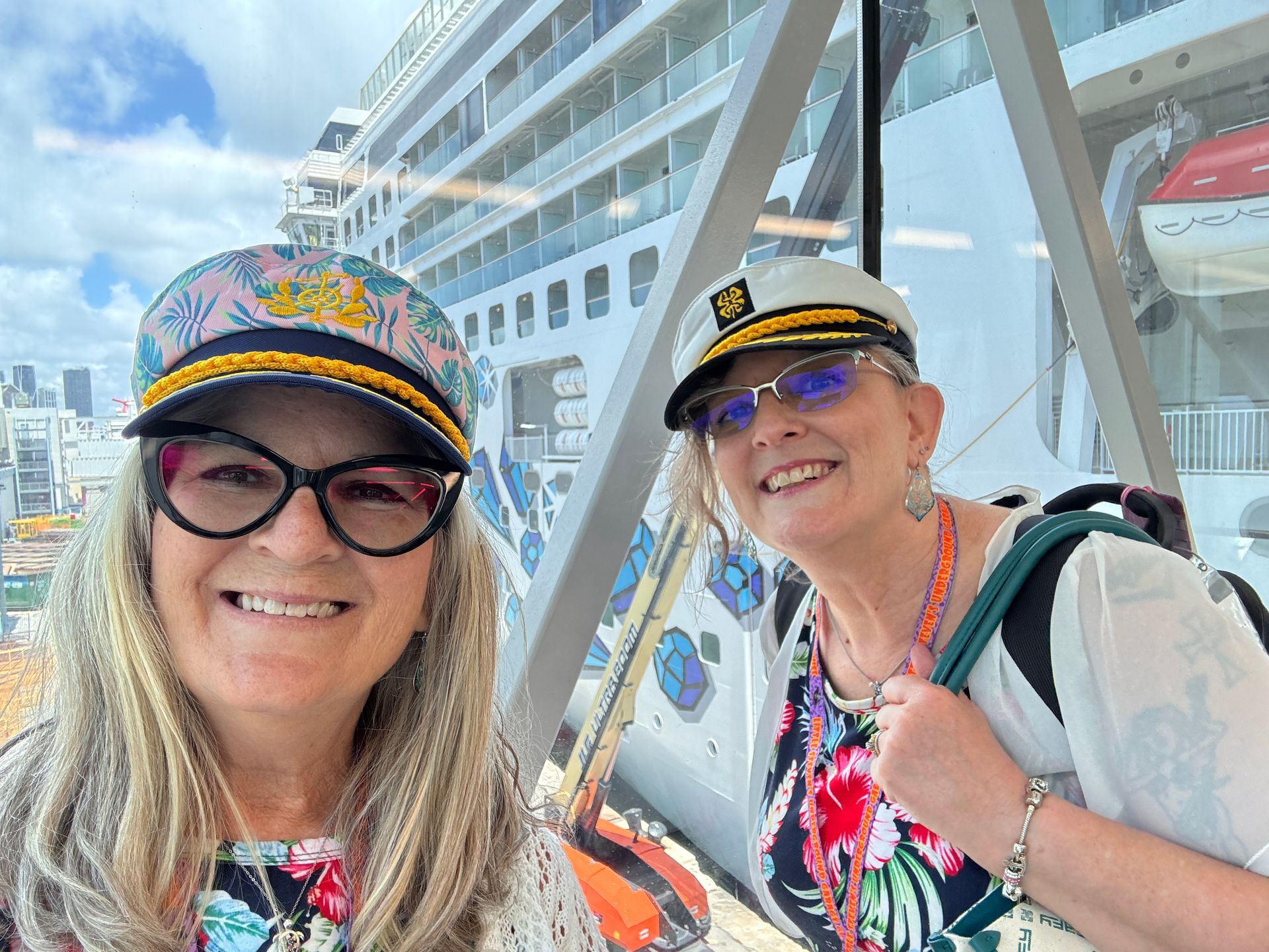 Two women are posing for a picture in front of a cruise ship.
