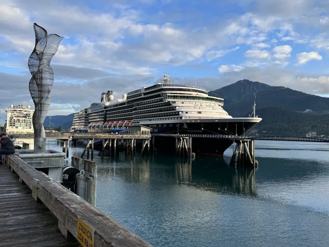 A large cruise ship is docked at a pier in a harbor.