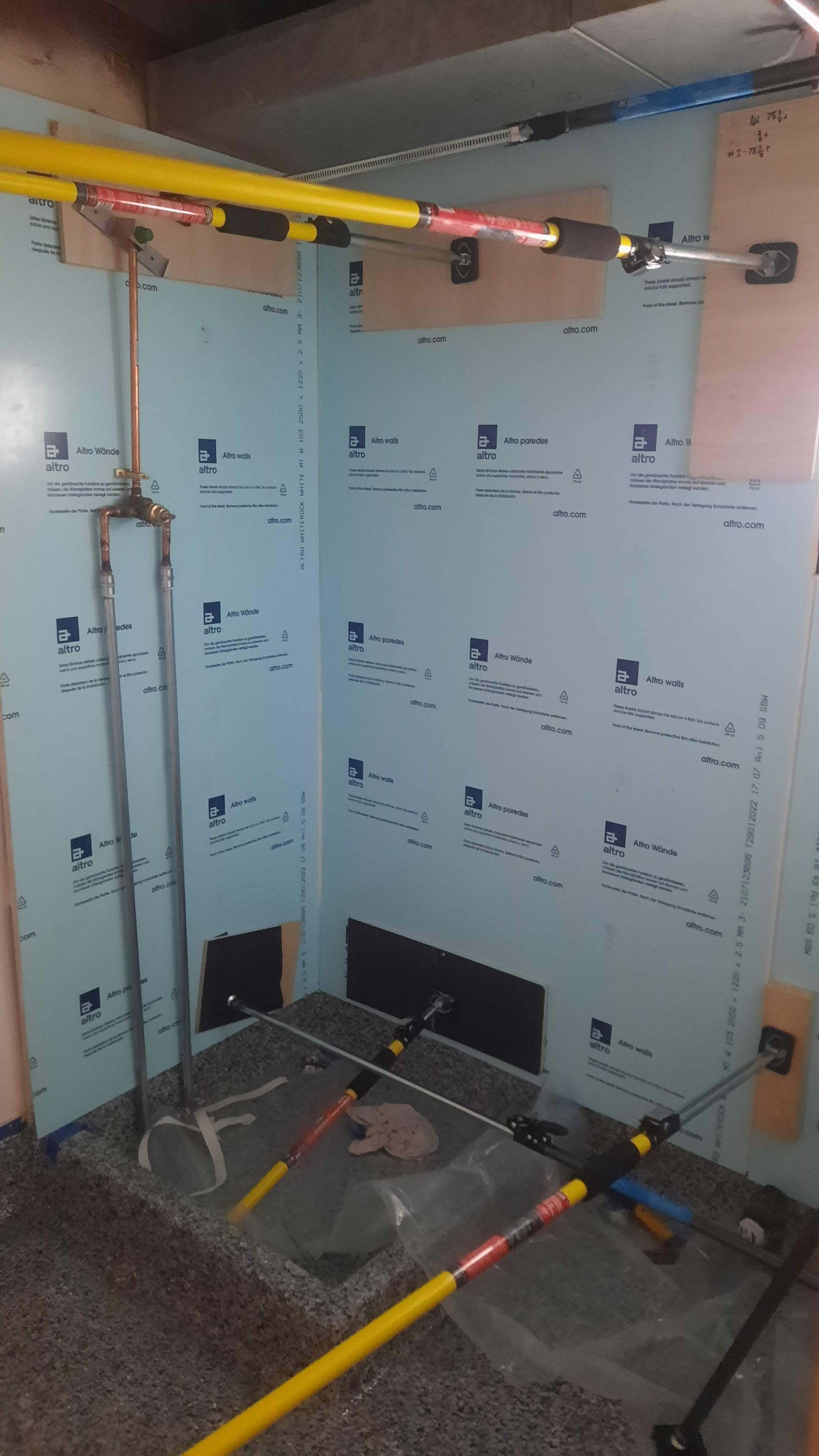 Blue insulated walls with plumbing and support beams in an unfinished basement corner.