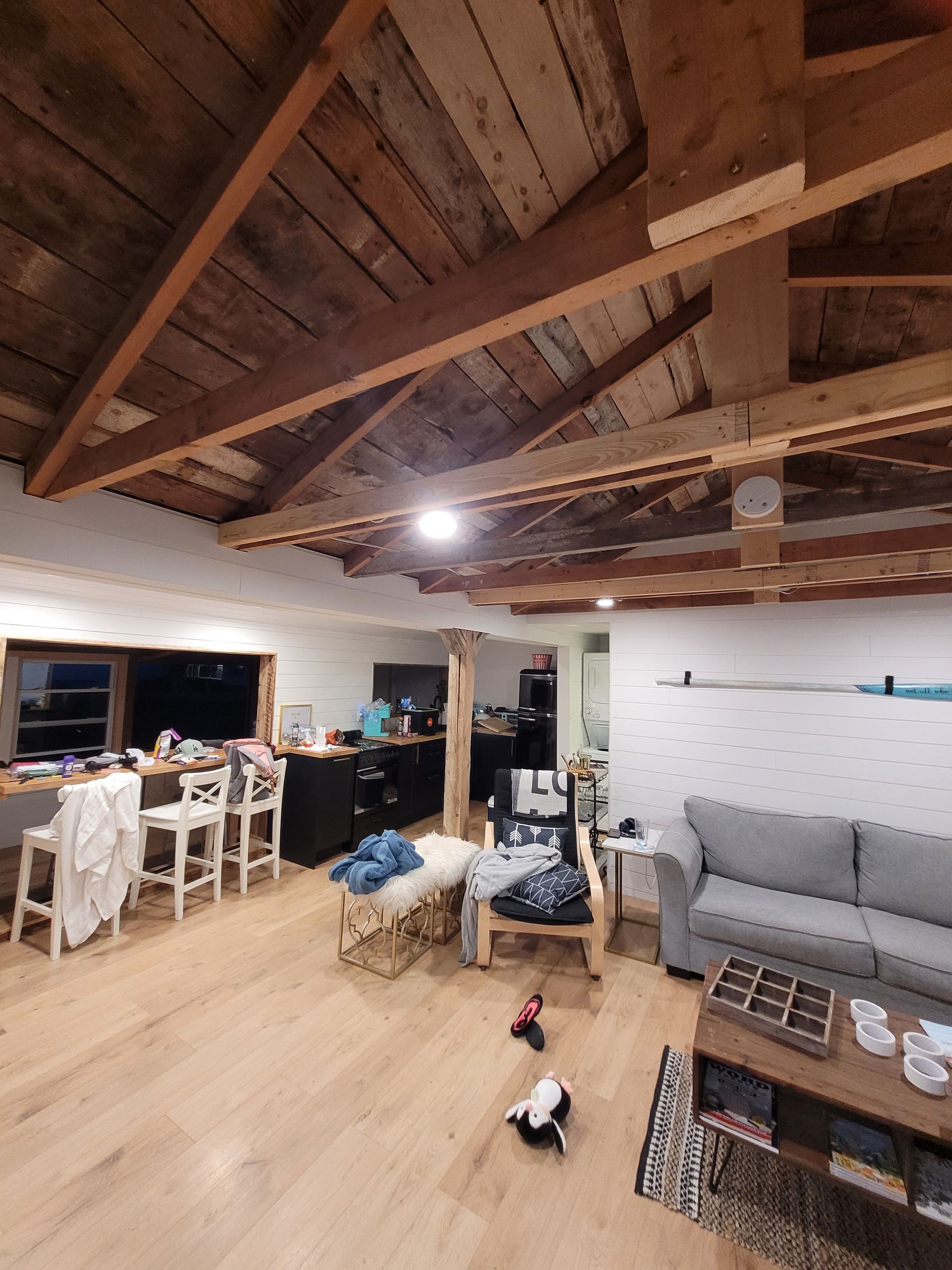 Interior with exposed wood ceiling, kitchen island, and living area with sofa and rug.