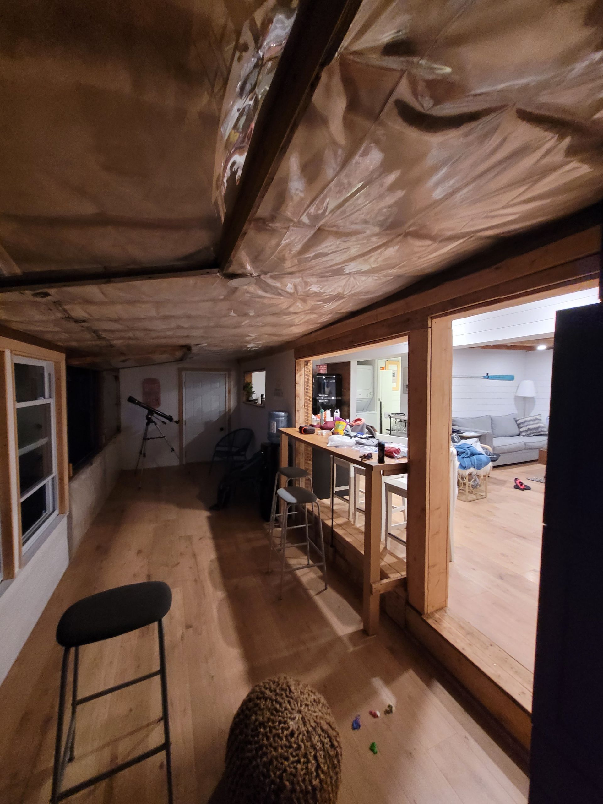 Basement interior with wood floors, open doorway, and bar with stools.