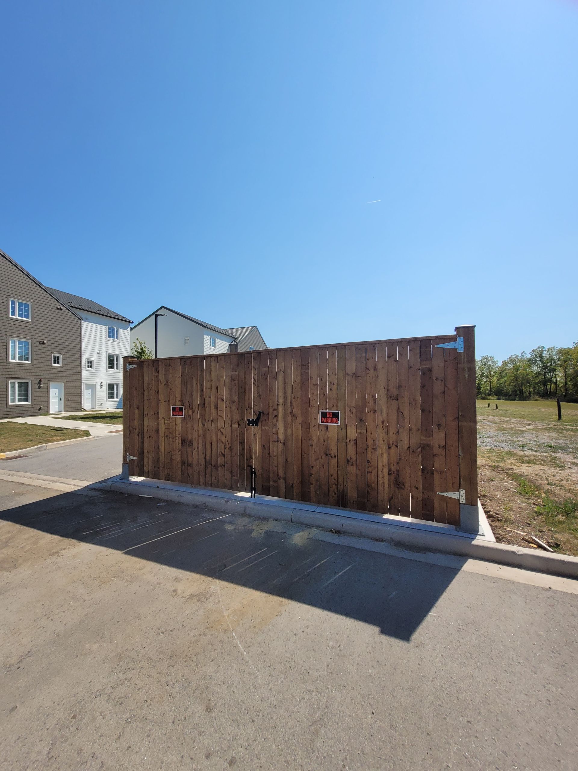 Wooden trash enclosure in front of apartment building. Sunny day, blue sky.