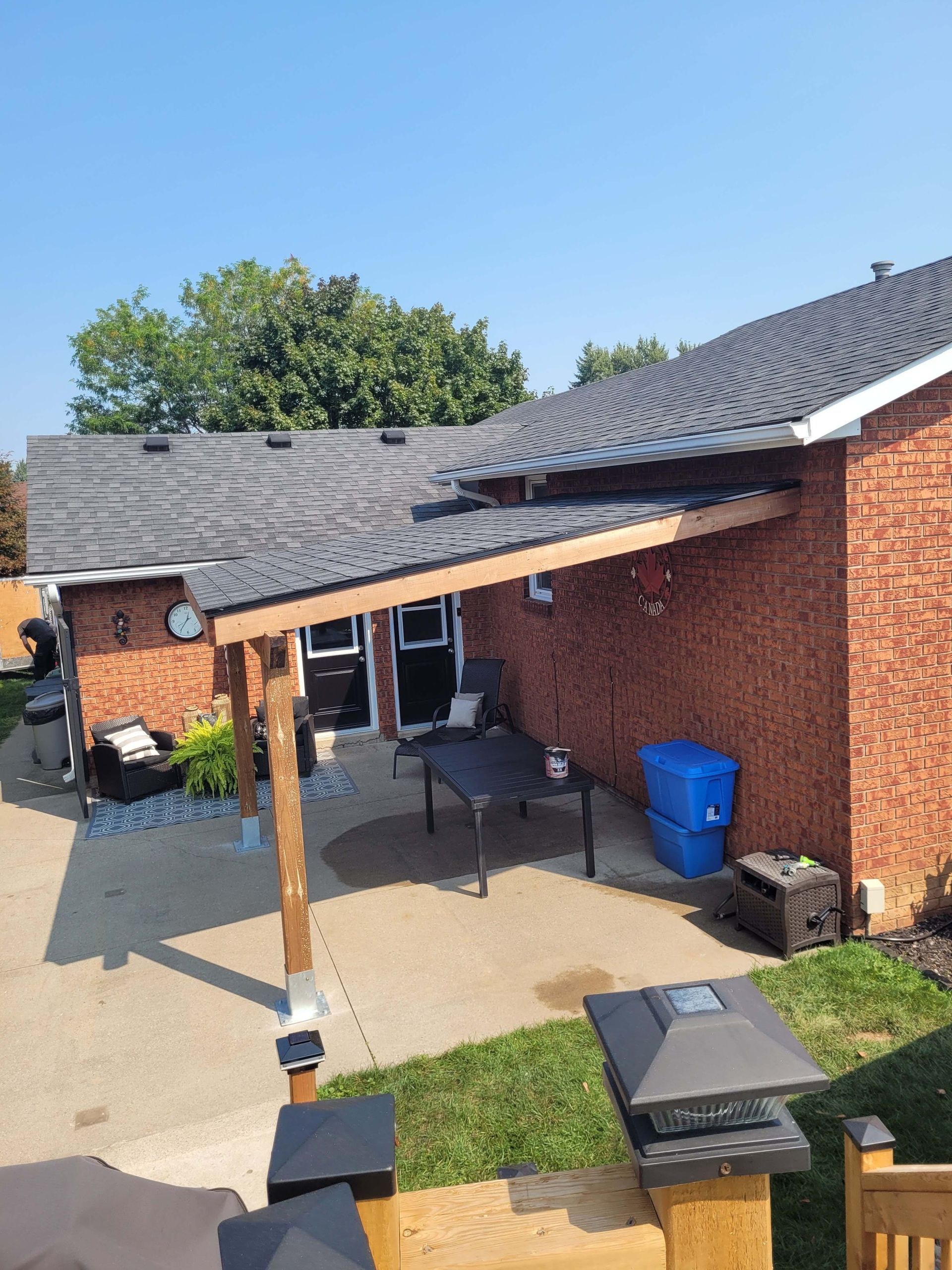 Brick house with a wooden patio cover; outdoor setting. Blue sky.