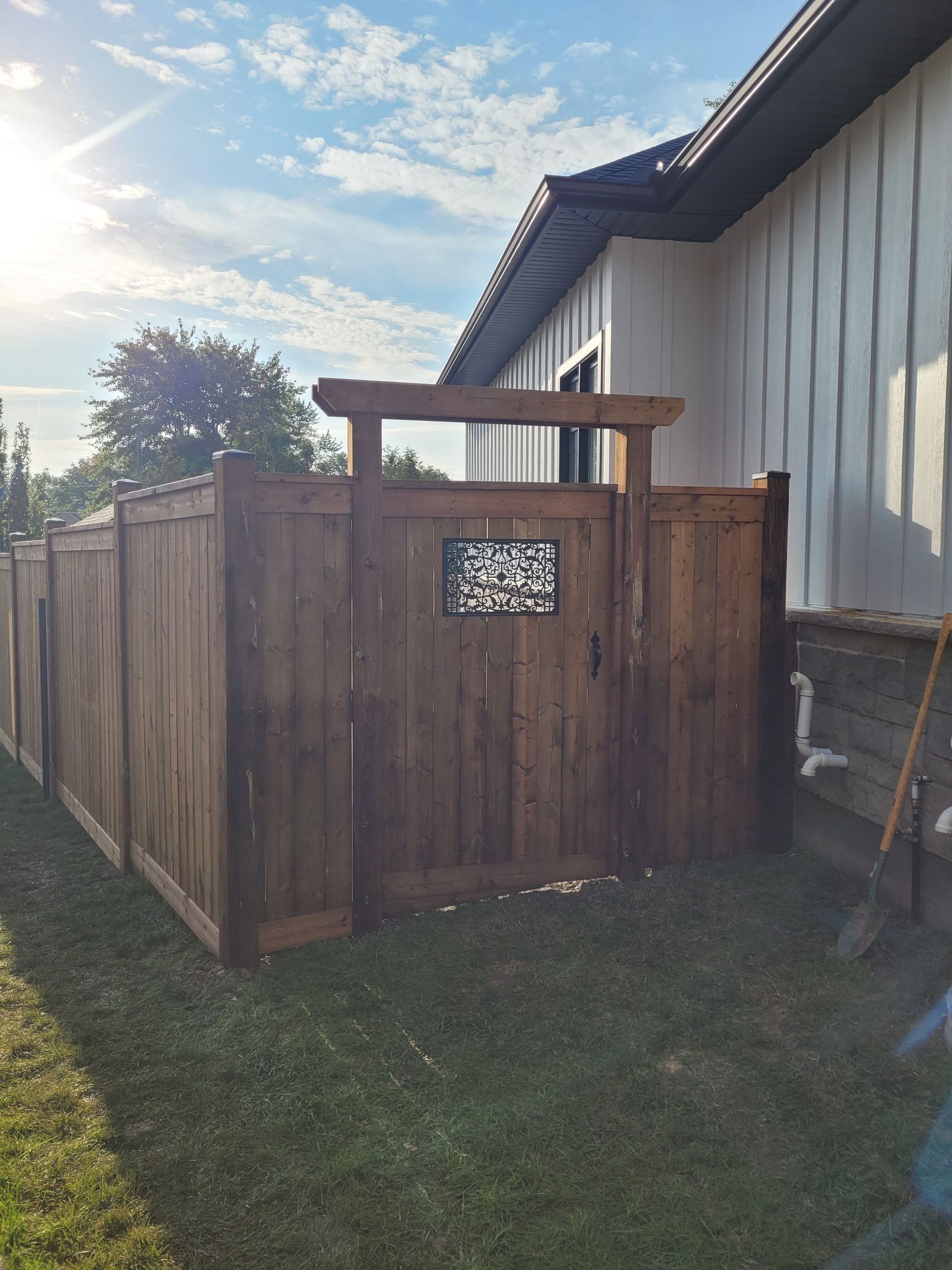 Wooden privacy fence with a gate beside a building, in a grassy yard.
