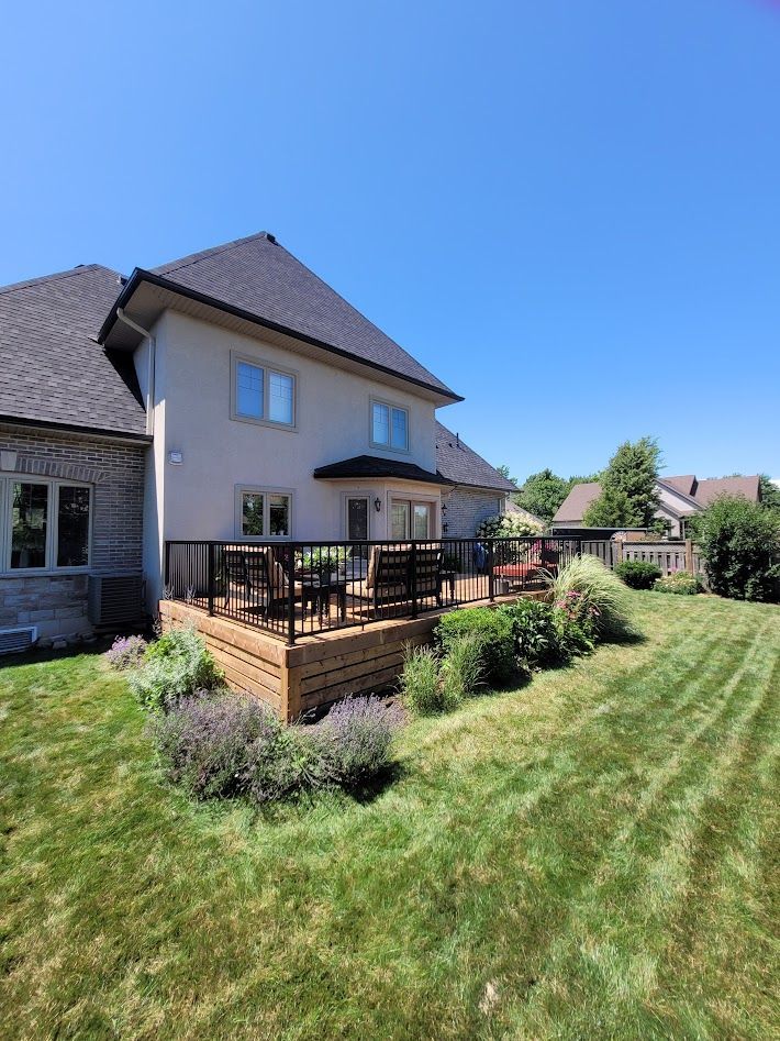Backyard scene with a pool, wooden fence, and concrete patio.