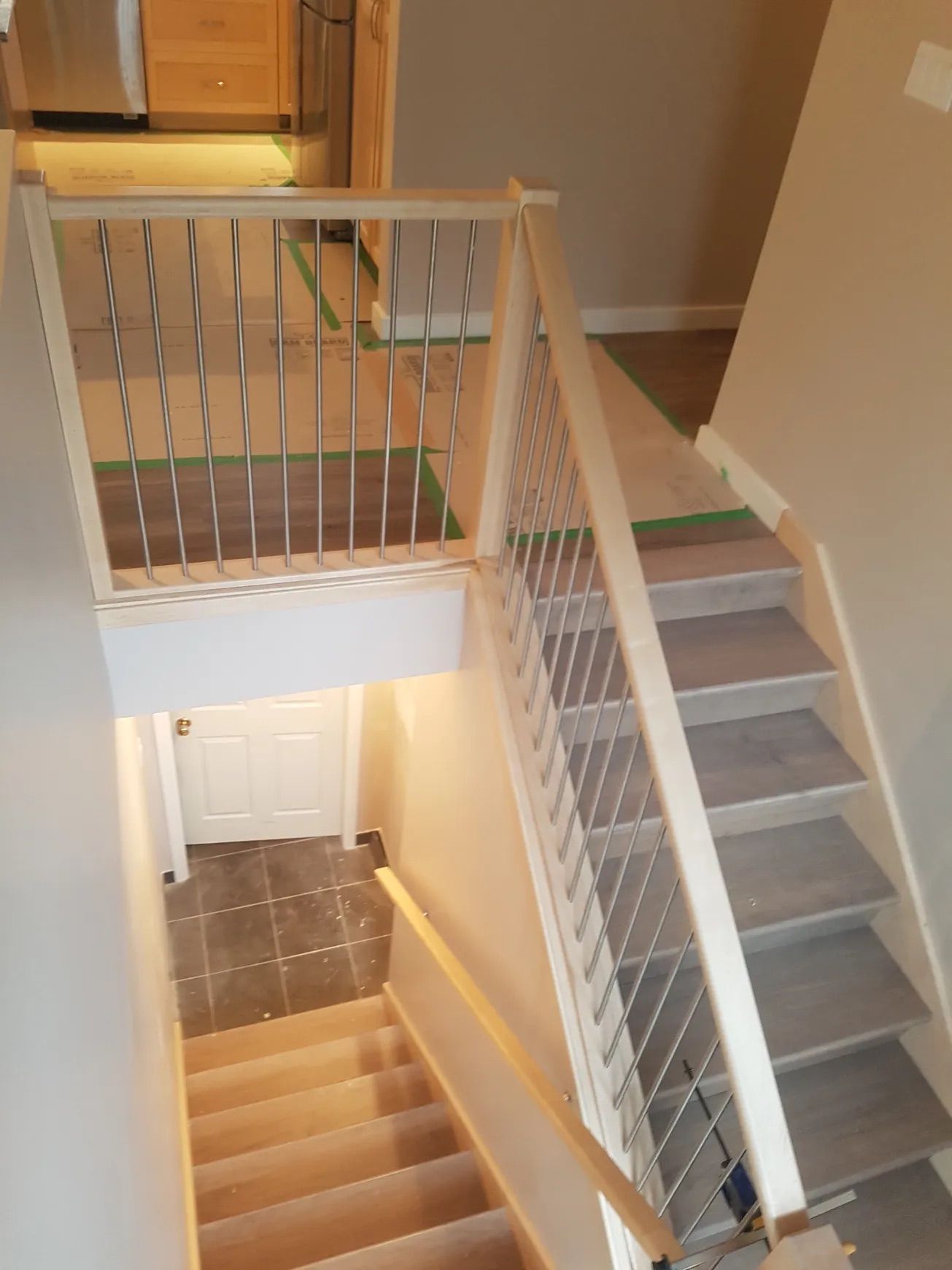 Interior staircase with light-colored wooden railings and gray steps. Metal spindles create a modern look.