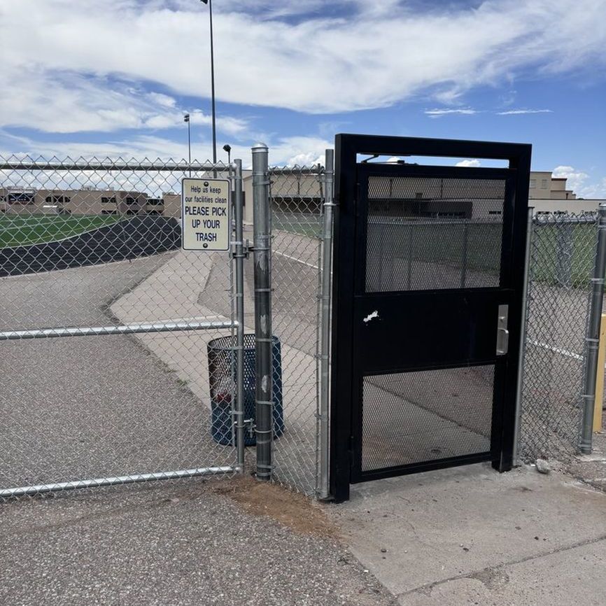 A chain link fence with a sign that says please pick up your trash