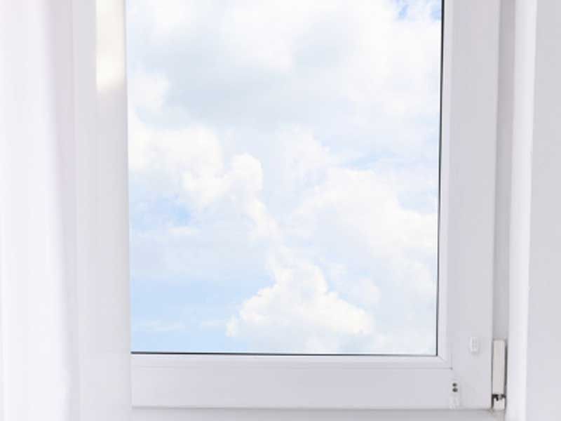 a white window with a blue sky and clouds visible through it .