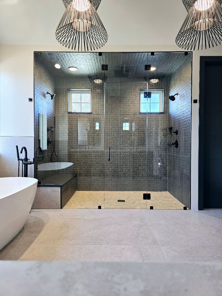 Luxurious modern bathroom with large glass shower, free-standing tub, and gray tile.