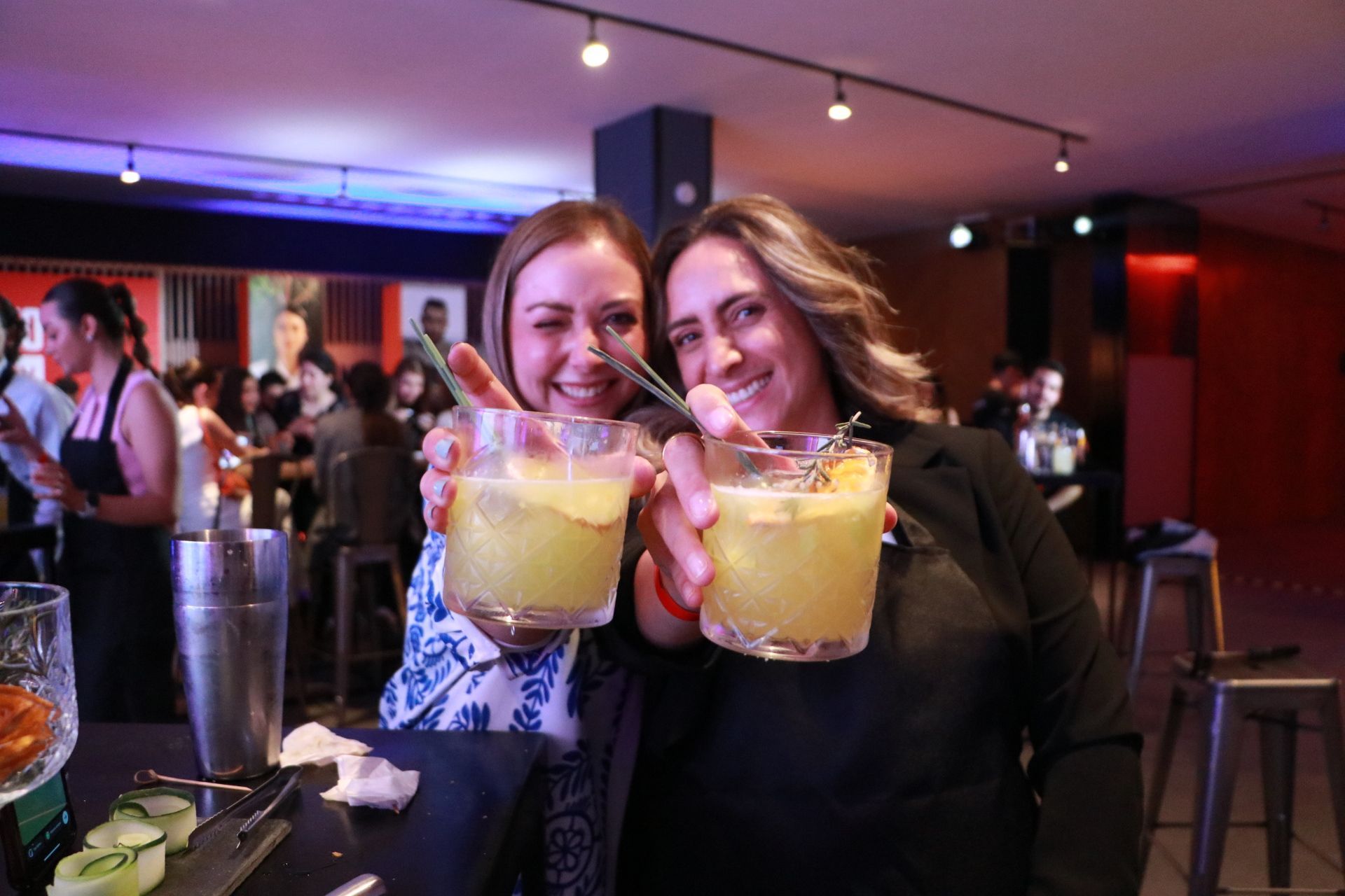 Duas mulheres estão segurando bebidas nas mãos em um bar.