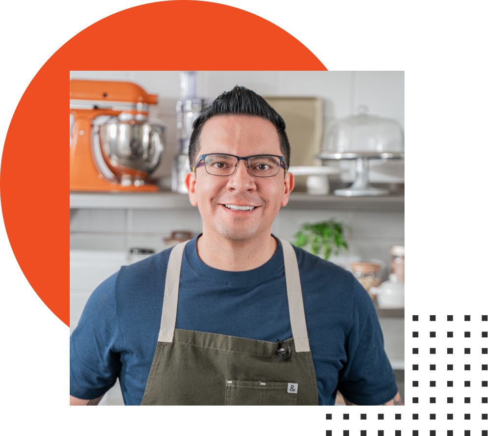 Um homem vestindo avental e óculos está sorrindo em uma cozinha.