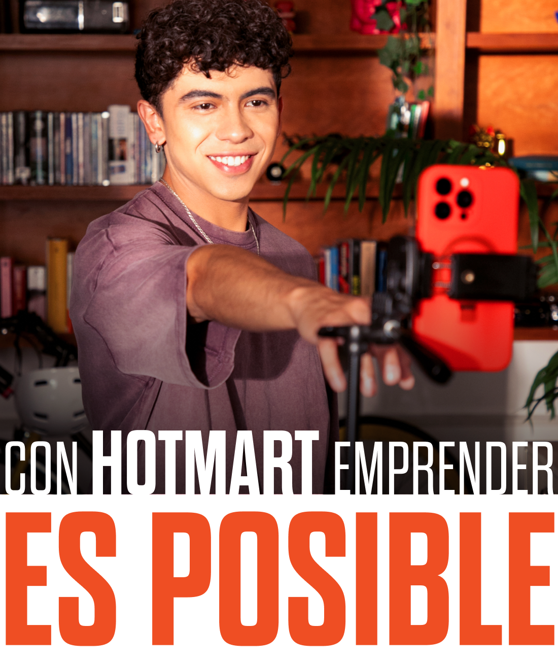 Um jovem está tirando uma foto com um telefone em um tripé com as palavras con hotmart emprender es posible na parte inferior