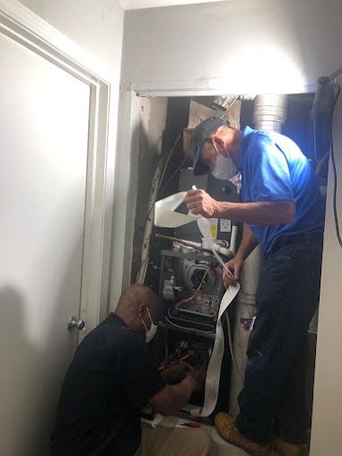 Two Men Are Working on A Heating System in A Room - Atlanta, GA - Dachi Mechanical