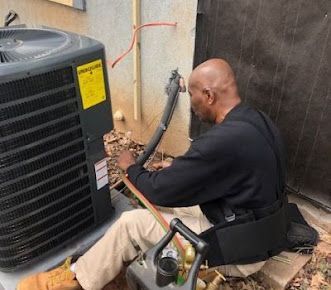 A Man Is Sitting on The Ground Working on An Air Conditioner - Atlanta, GA - Dachi Mechanical