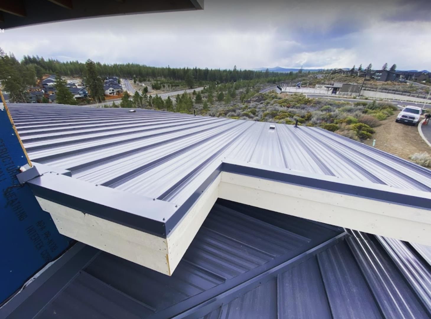 An aerial view of a metal roof with a valley in the background.