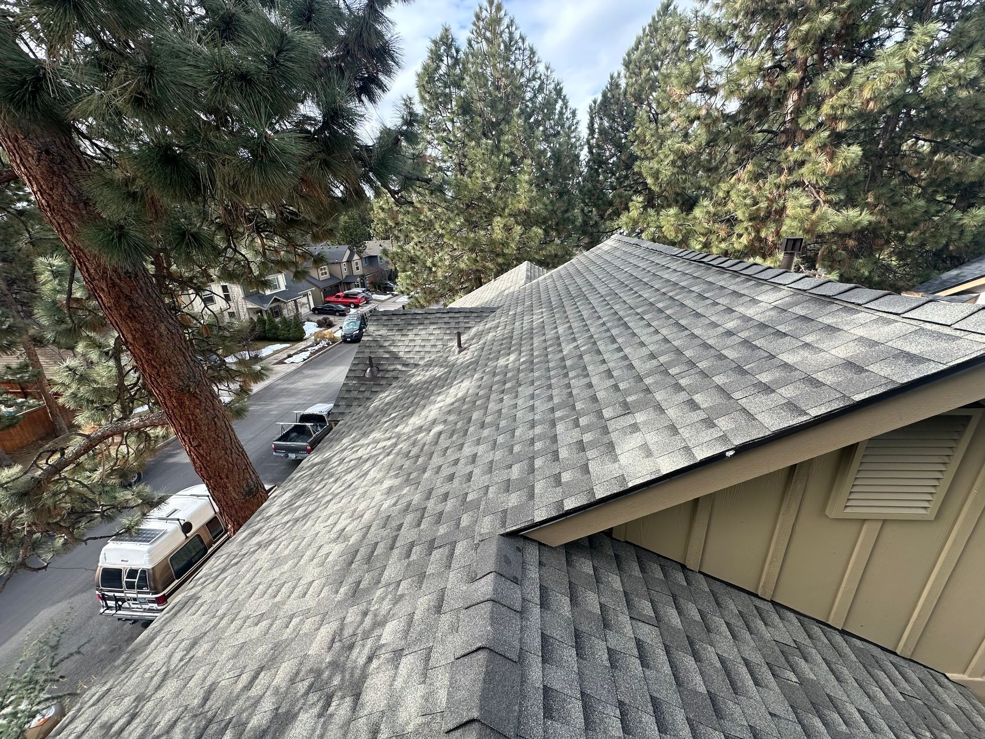An aerial view of a roof of a house with trees in the background.