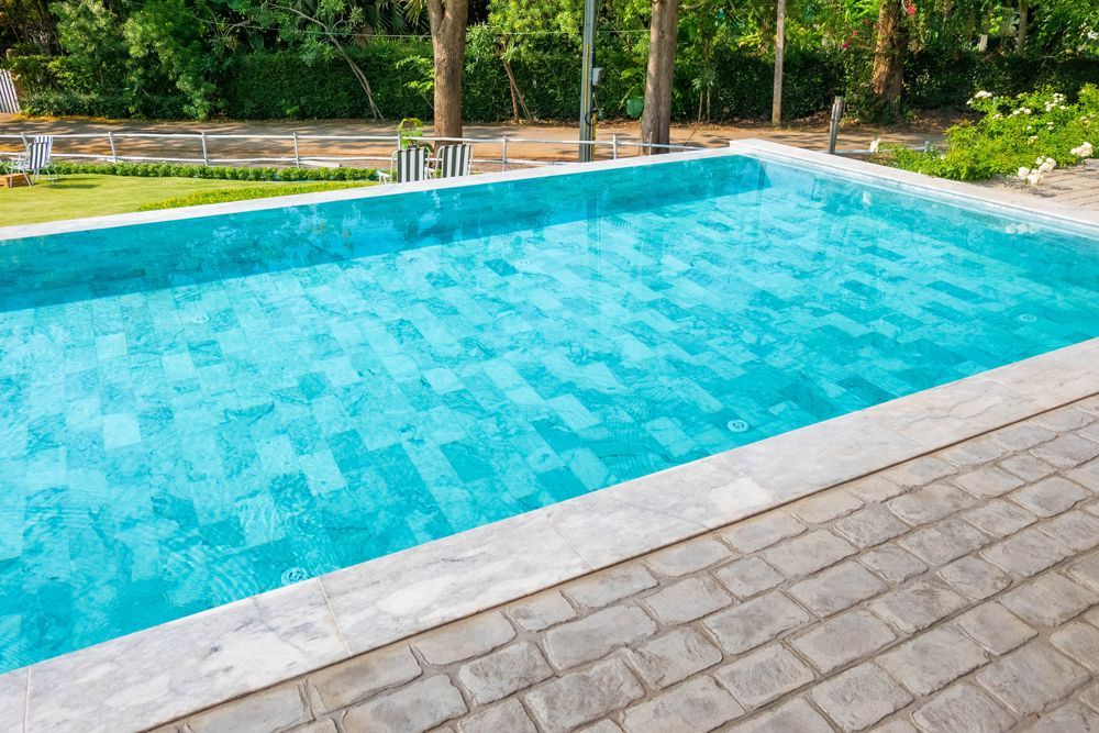 A large swimming pool filled with blue water and surrounded by trees.